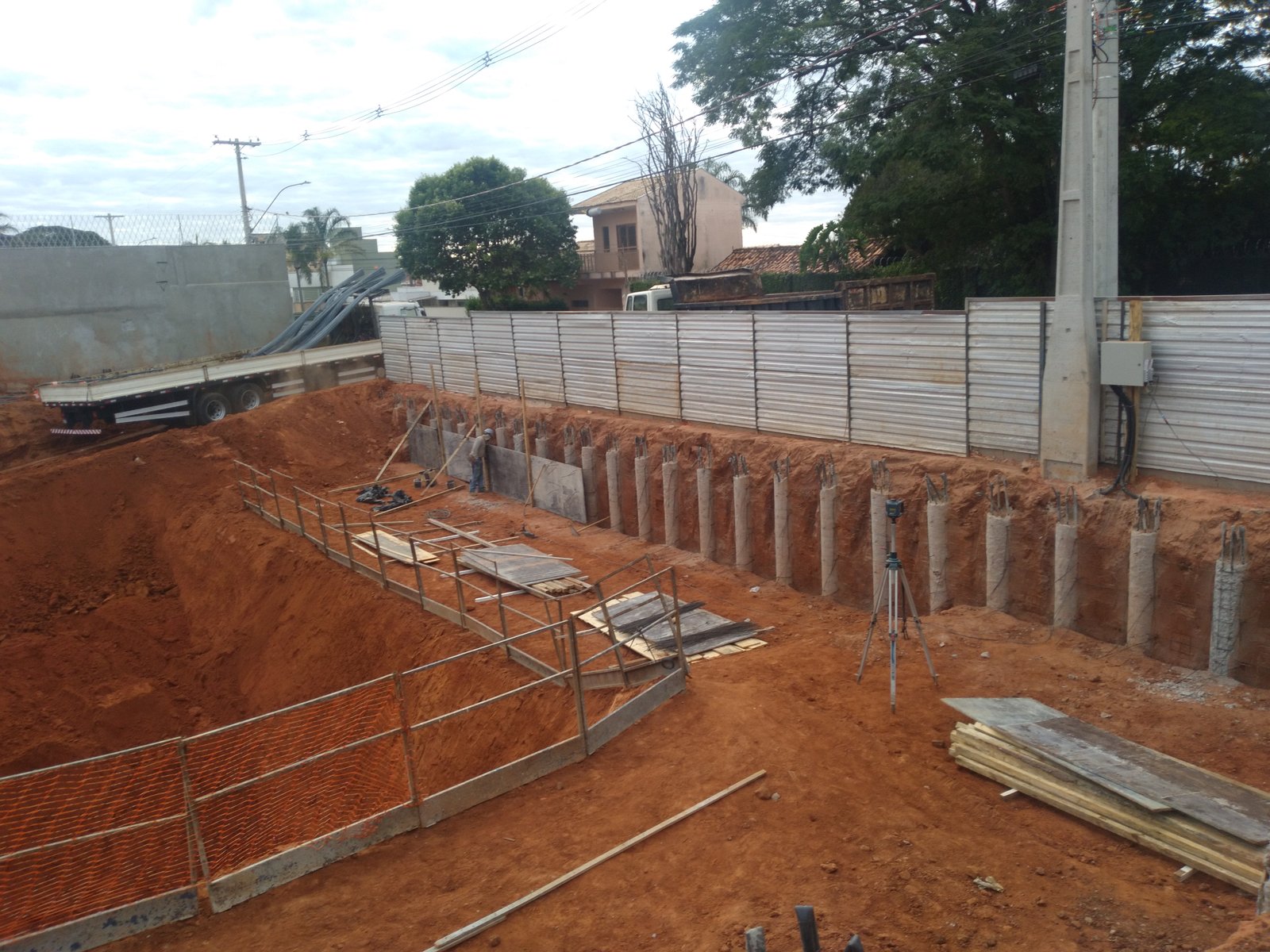 Vala escavada com fileira de estacas de concreto e nível a laser