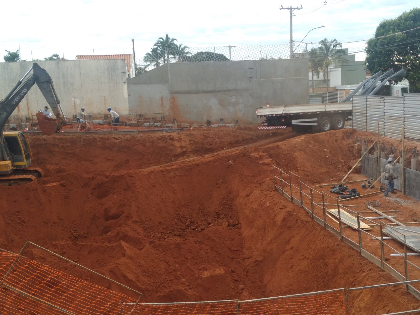 Escavação da obra com retroescavadeira, caminhão e equipe de trabalho
