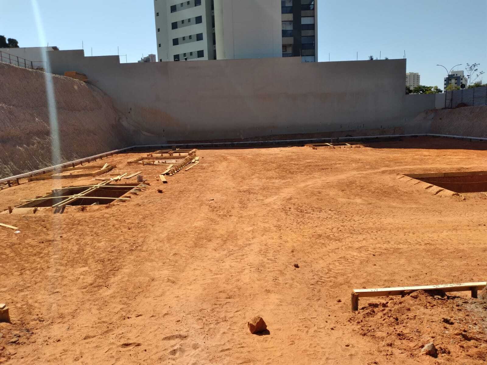 Terreno escavado com muro de contenção e marcação das fundações